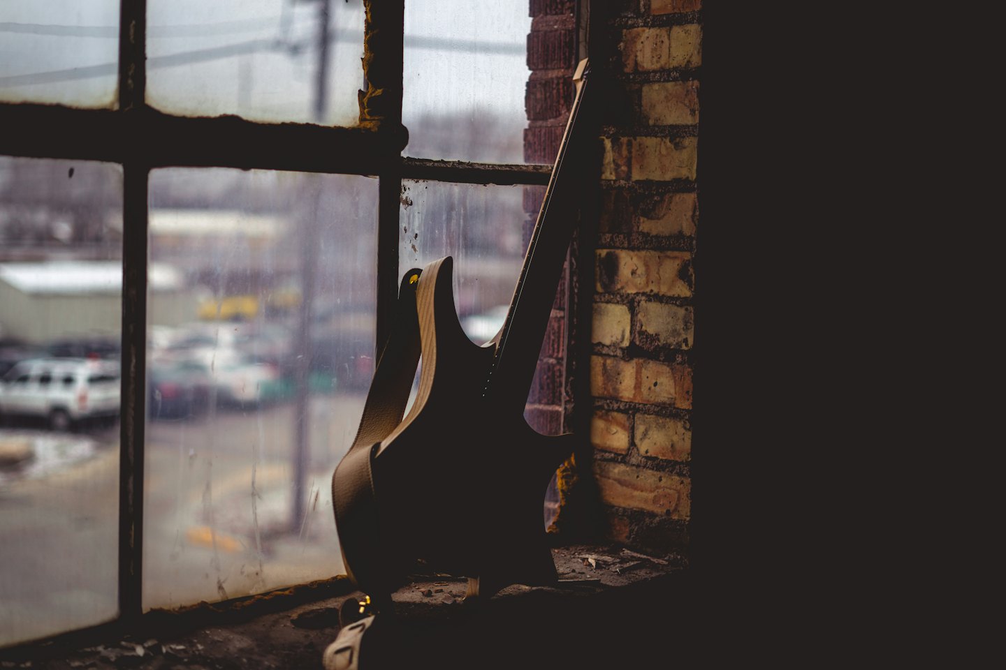 An electric guitar leans against a weathered brick wall.